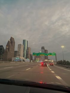 cars driving down the highway with tall buildings in the background