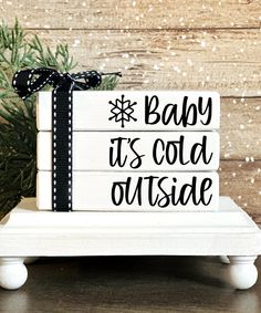 a wooden sign that says baby it's cold outside with a bow on top