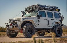 a white jeep parked in the middle of a dirt road with its roof rack on