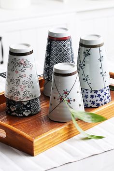 four vases sitting on top of a wooden tray