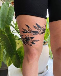 a woman's leg with black ink on it and some plants in the background