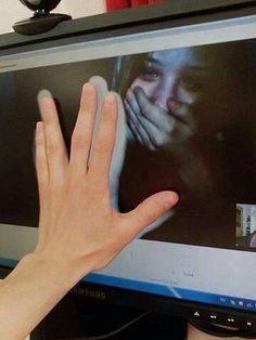 a person's hand reaching up towards a television screen with the image of a woman on it