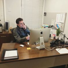 a man sitting in front of a computer on top of a desk with headphones