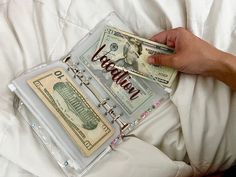 a person is laying in bed with some money