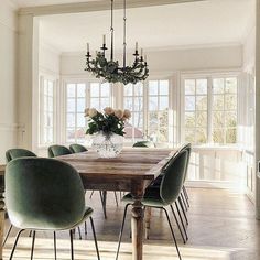 a dining room table with green chairs and a chandelier hanging from the ceiling