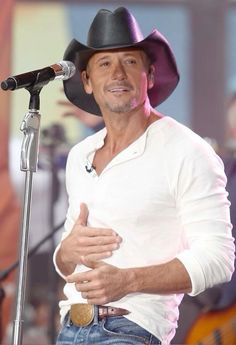 a man wearing a cowboy hat standing in front of a microphone