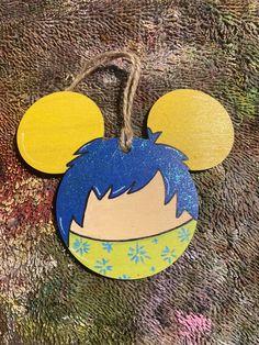 a mickey mouse ornament with blue hair and yellow ears on a brown background