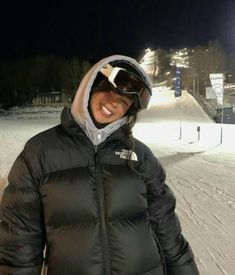 a woman standing on top of a snow covered slope wearing skis and a jacket