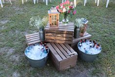 several buckets filled with ice sitting on top of a wooden table in the grass