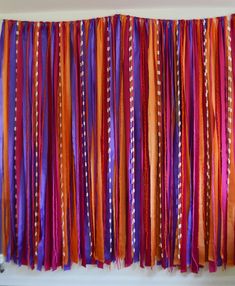 an orange, purple and red curtain hanging on a wall