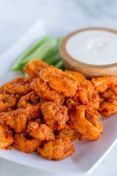 a white plate topped with fried chicken next to celery