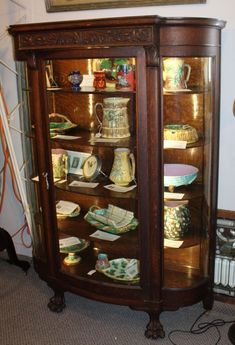 an old china cabinet with many plates and bowls on it's glass front doors