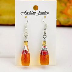 a pair of earrings with orange and yellow bottles