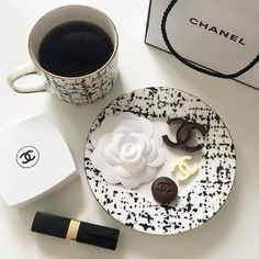 a white plate topped with cookies next to a cup of coffee and a black and white bag