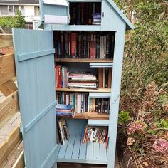 a book shelf made out of an old shed with doors open and books on the shelves