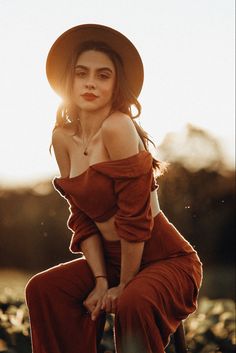 a woman wearing a brown hat sitting on top of a wooden chair in the sun