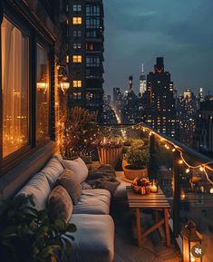 an apartment balcony with lights strung from the ceiling and couches on the outside, overlooking cityscape at night