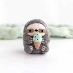 a small stuffed animal with an ice cream cone in it's mouth on a white surface