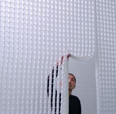 a man standing in front of a white screen holding something up to his face with both hands