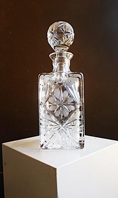 a clear glass bottle sitting on top of a white box