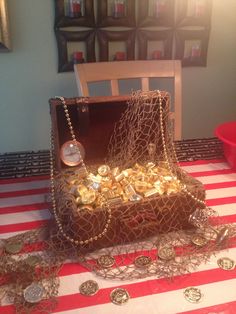 a table topped with a wooden box filled with lots of gold coins on top of a red and white striped table cloth