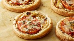 four small pizzas sitting on top of a piece of parchment paper