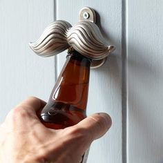 a person is holding a beer bottle in front of a door handle with a mustache on it