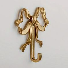 a gold metal hook with a bow on it's end and the letter j in the middle