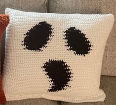 a crocheted pillow with black and white paw prints on it, sitting on a couch