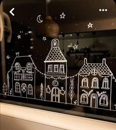 an image of a window with houses drawn on it and stars in the night sky