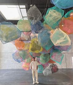 a man standing in front of a large amount of plastic balls hanging from the ceiling