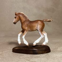 a toy horse is standing on a wooden base