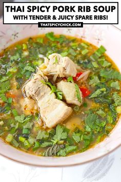 a white bowl filled with chicken and vegetable soup on top of a table next to a spoon