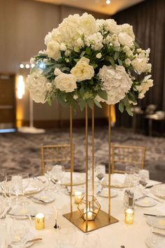 there is a tall vase with white flowers in it on top of a round table