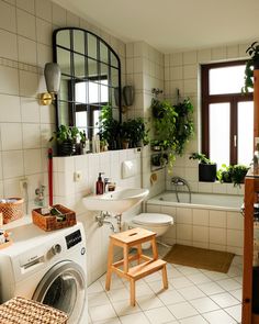 a washer and dryer in a bathroom with plants on the window sill