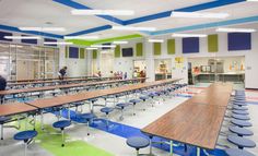 an empty cafeteria with tables and blue chairs