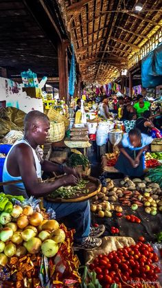 an outdoor market with people shopping for fruits and vegetables