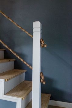 the rope is tied to the top of the stair railing in front of the blue wall