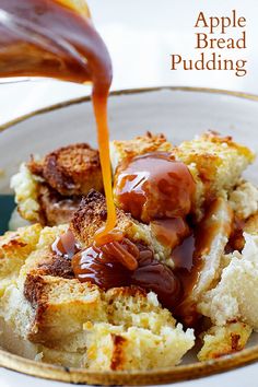 an apple bread pudding being poured on top of it in a white bowl with caramel sauce