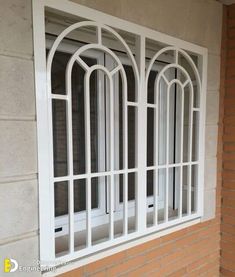 a white window on the side of a brick building with arched windows and glass panes