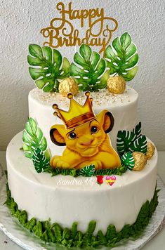 a birthday cake with a lion wearing a crown on it's head and palm leaves around the edges