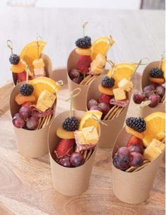 small cups filled with fruit and cheese on top of a wooden tray next to a fork