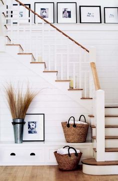 two baskets on the floor in front of stairs with pictures on the wall behind them