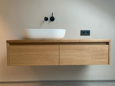 a bathroom sink sitting on top of a wooden counter next to a wall mounted faucet