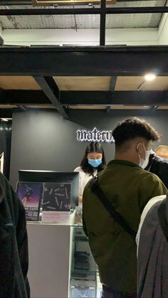 people wearing face masks are standing in front of a display case with information on it