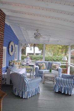 the porch is decorated with blue and white striped couches, chairs, and tables