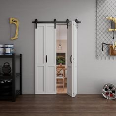 an open door in a room with wooden floors and white walls, next to a bike