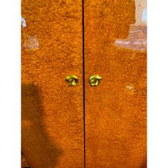 a wooden door with two green knobs on it's sides and an orange wall in the background