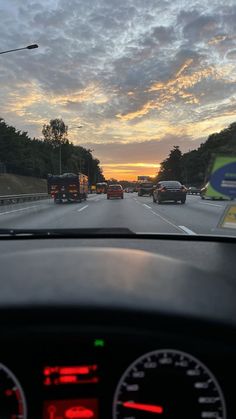 the sun is setting behind some cars driving down the road with traffic on both sides