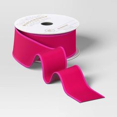 a spool of bright pink ribbon on a white background with a roll of tape